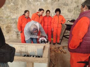 Mujeres otomíes observando demostración de herramienta eléctrica en curso de carpintería